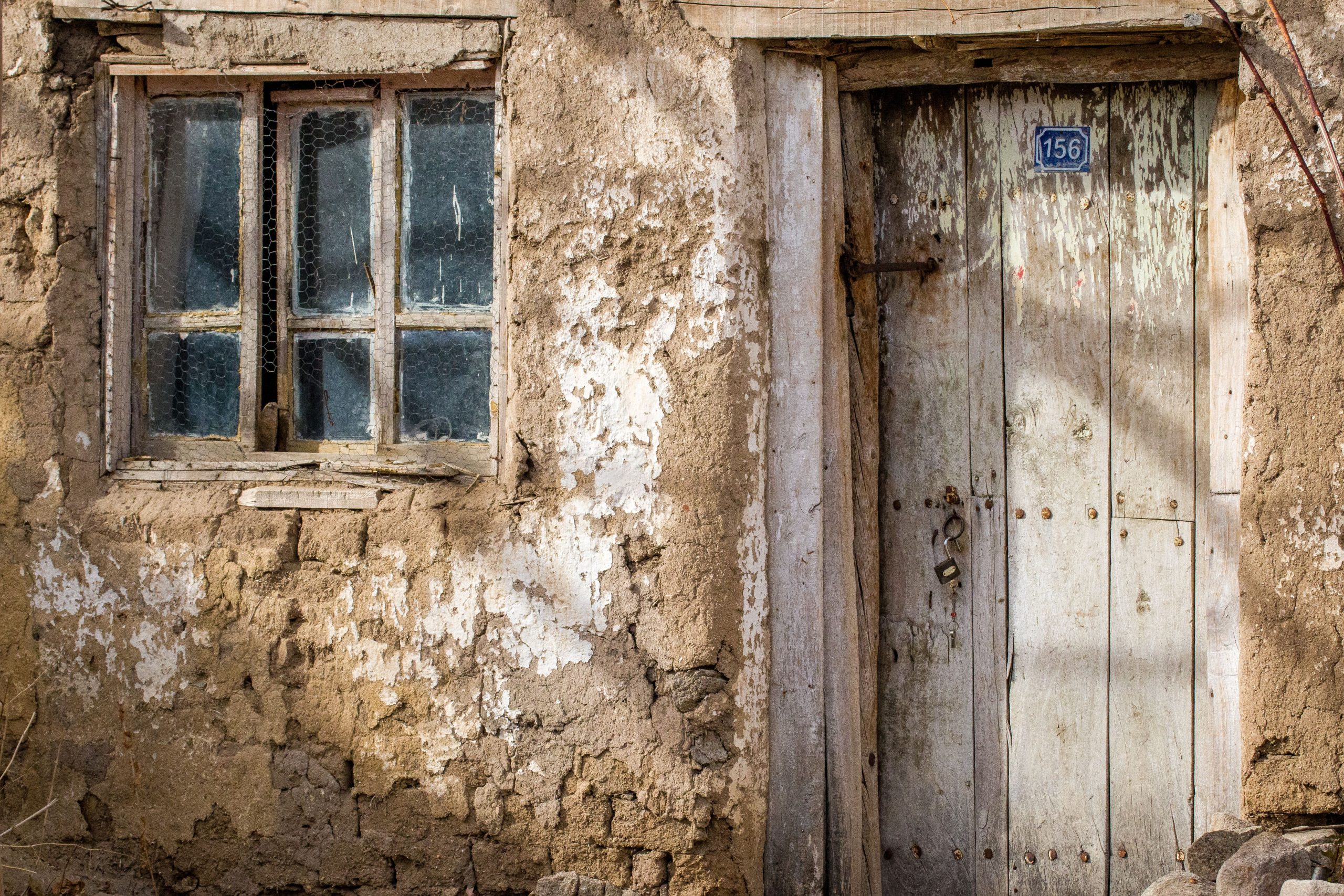 Façade dégradée avec porte bois et fenêtre fissurée