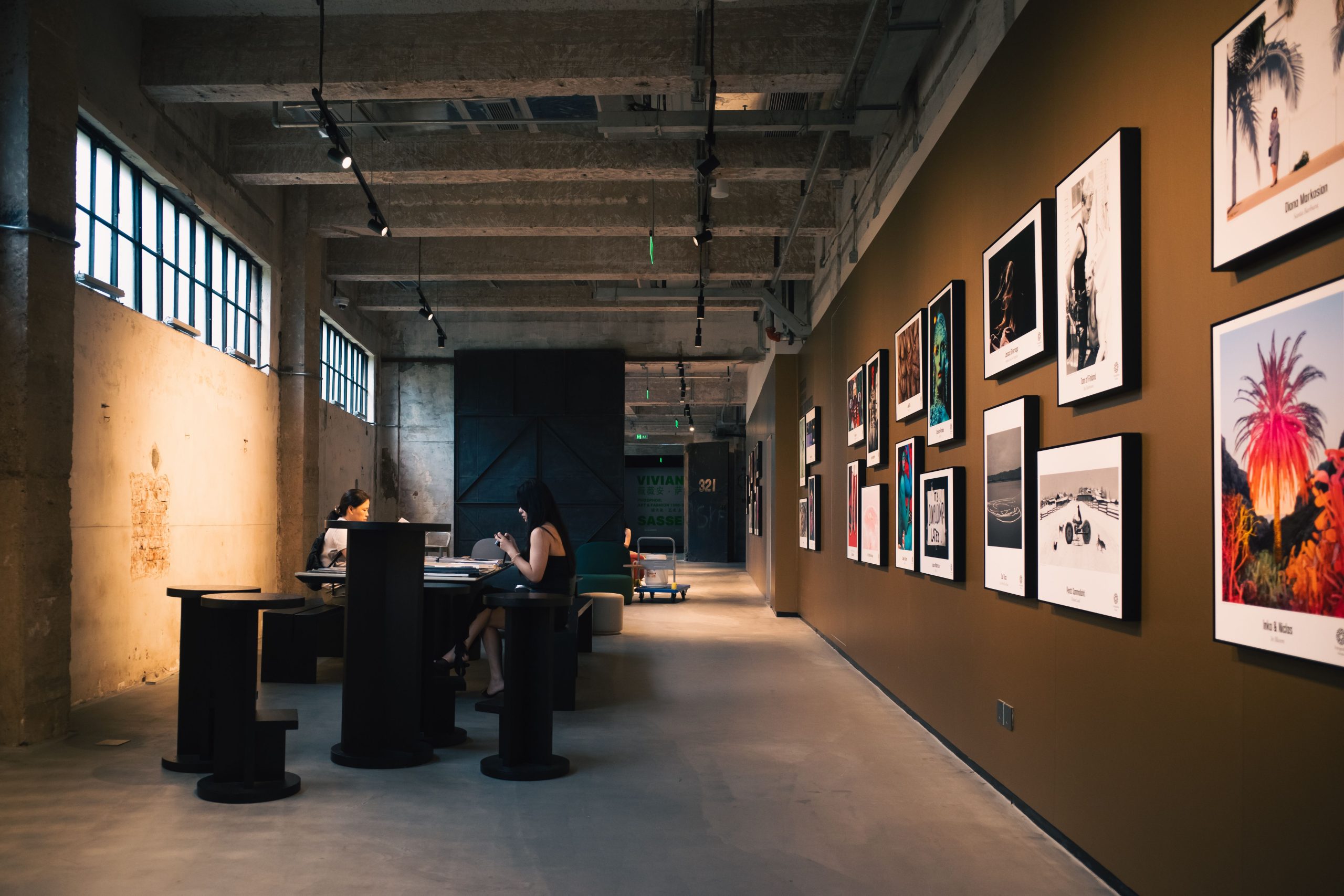 Galerie d'art avec œuvres encadrées et visiteurs assis