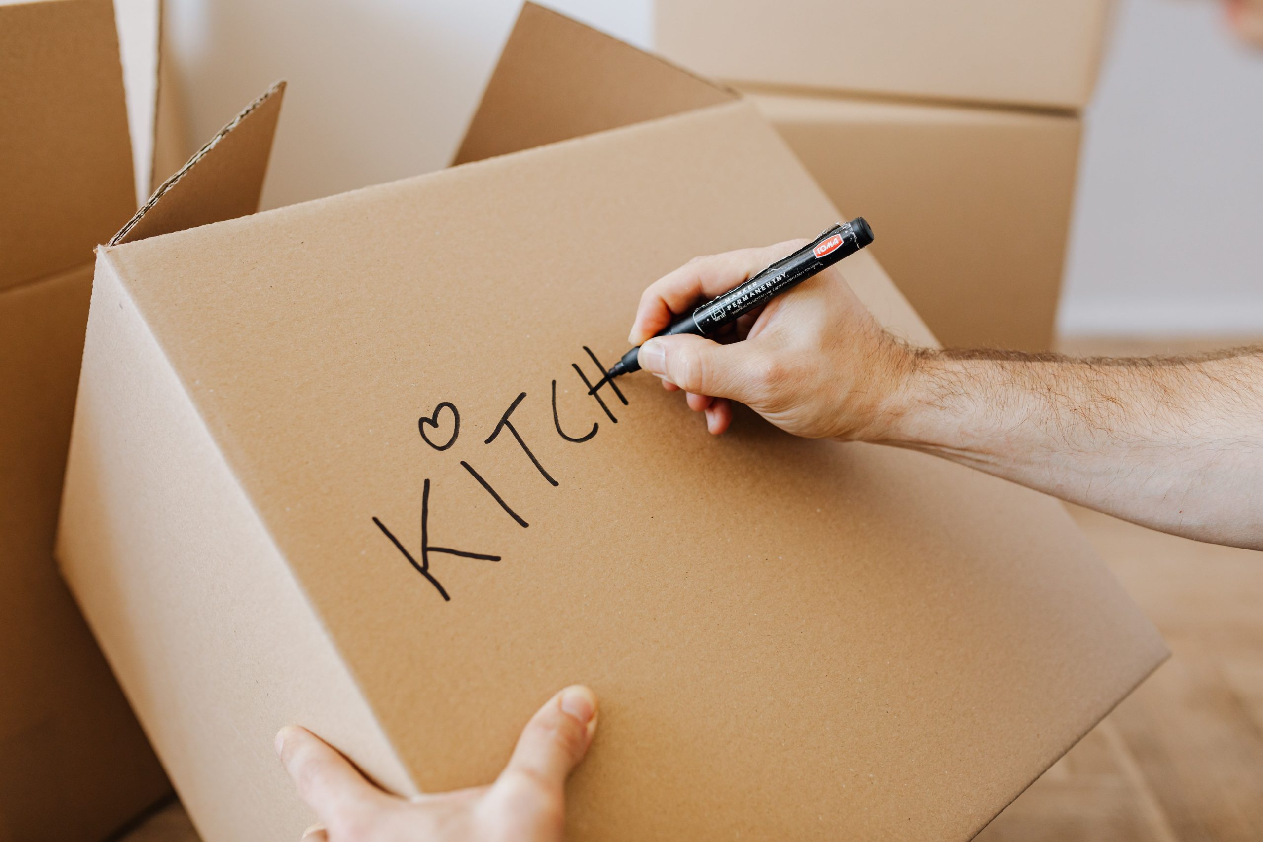 Homme écrivant sur un carton lors de la préparation du déménagement