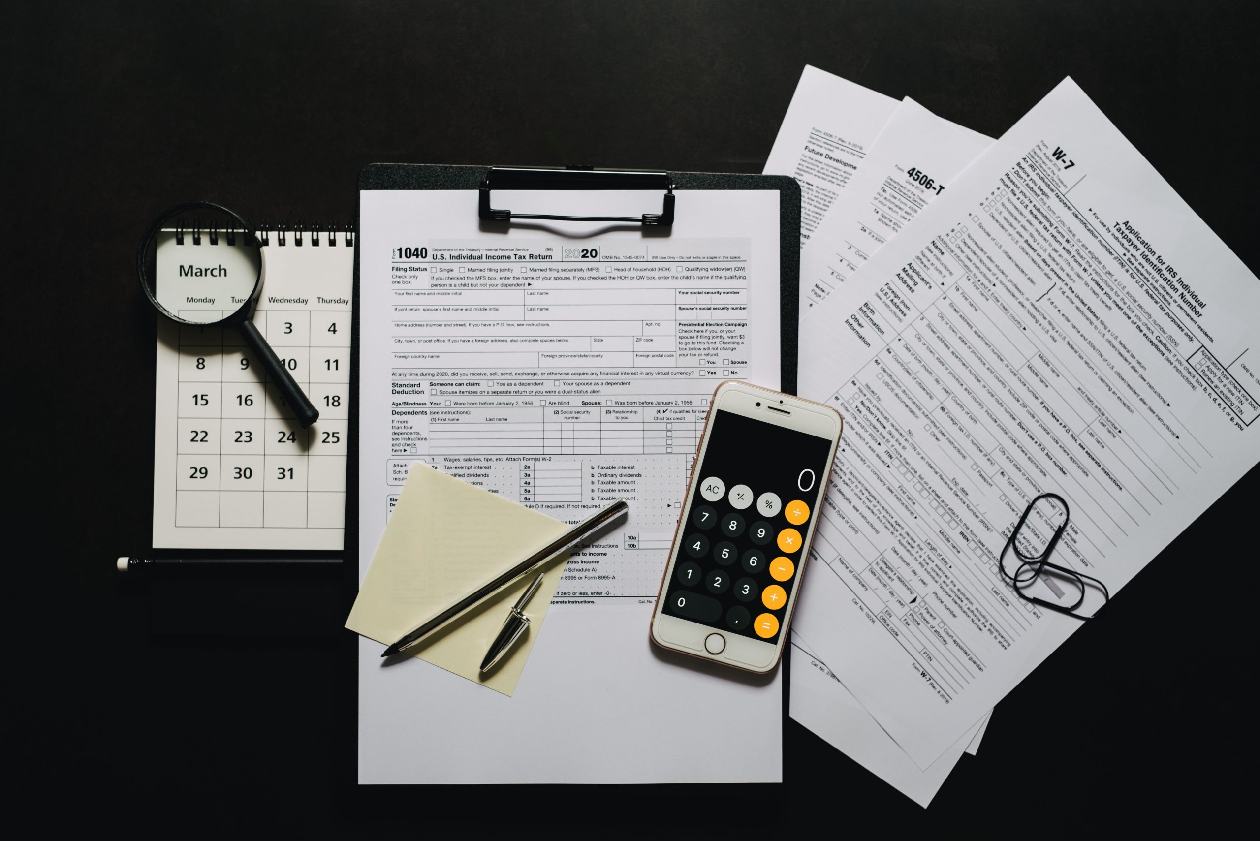 Documents fiscaux, calculatrice et loupe sur surface noire